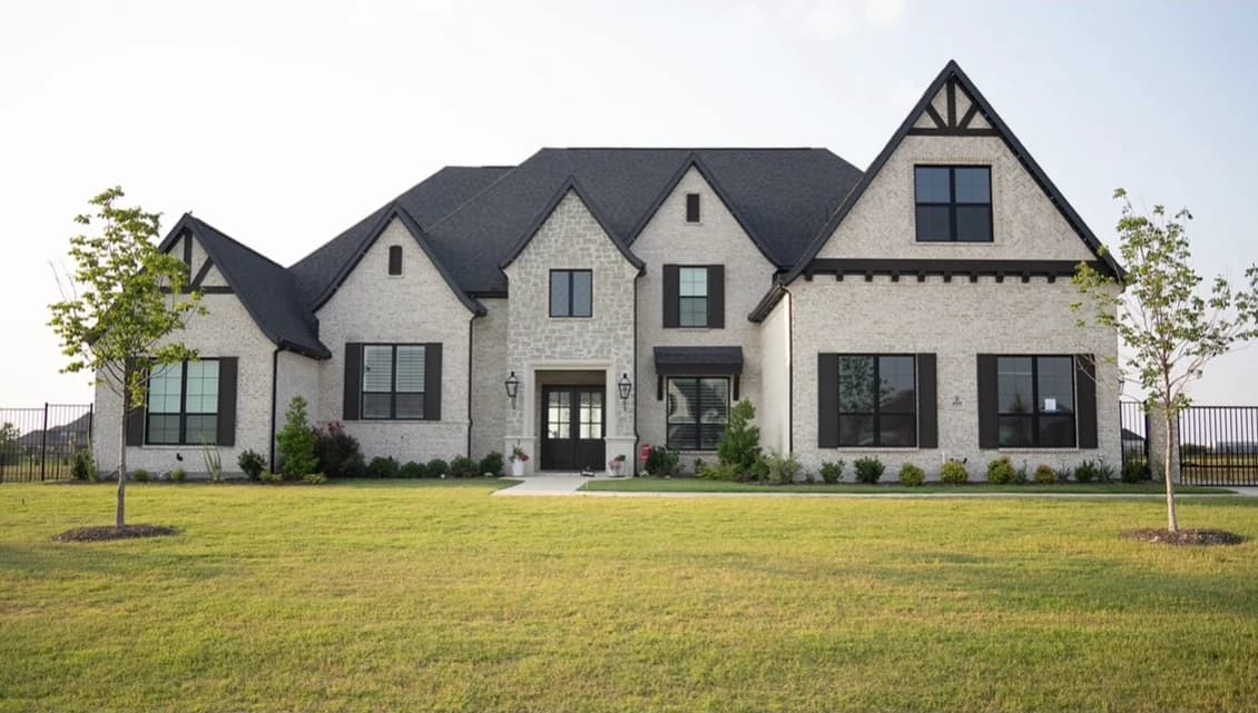 A stone-front home in daylight before lighting installation.
